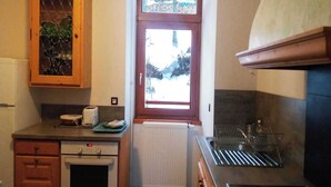 Une cuisine compacte avec un meuble en bois, une fenêtre offrant une vue agréable, un four encastré et un égouttoir à vaisselle.