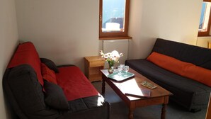 Un salon chaleureux avec un canapé, un fauteuil et une petite table sur laquelle est posé un vase de fleurs.