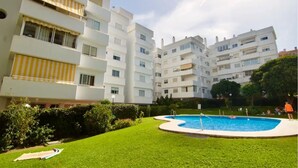 A residential building with a swimming pool surrounded by a well-maintained lawn.