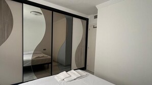 A modern bedroom with a bed, a wardrobe, and a mirror.