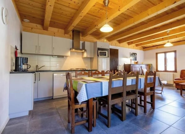 Una cucina con travi in legno, un tavolo da pranzo con sedie, un forno a microonde e pensili.