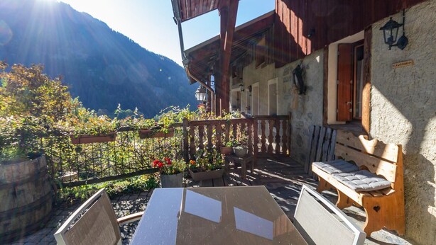 A rustic wooden building with a balcony overlooking a mountainous landscape.