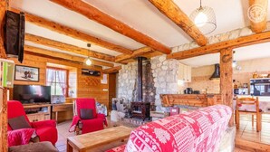 Un acogedor interior de cabaña con chimenea de piedra, mobiliario de madera y un televisor.