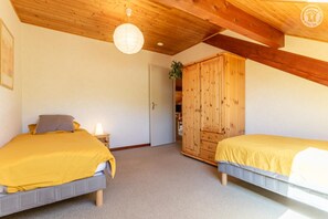A bedroom with two beds, a wooden wardrobe, and a ceiling light. - Le Talapet - Poppy (ALBIEZ MONTROND)