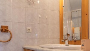 Een badkamer met een houten wastafelmeubel, een spiegel en een handdoekhouder.