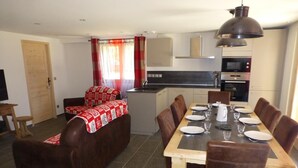 A modern apartment with a dining area, kitchenette, and a cozy living space. - LE REFUGE DU BACHAL N°1 (NOTRE DAME DE BELLECOMBE)