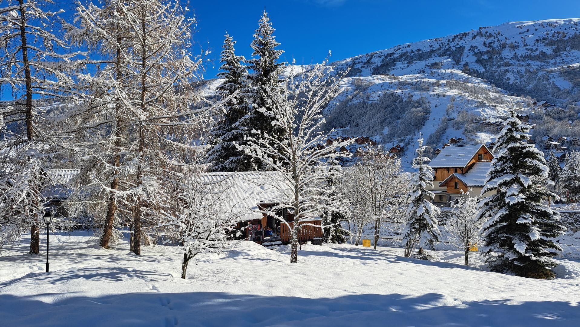 Un paysage enneigé avec une cabane en bois et une montagne en arrière-plan.