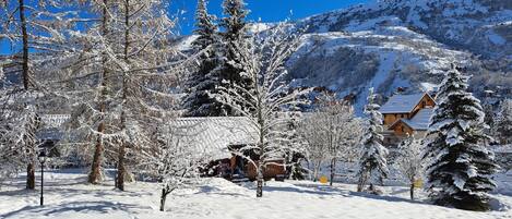A snow-covered landscape with a wooden cabin and a mountain in the background.