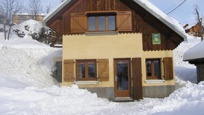 A two-story wooden building with a sloped roof, a sign indicating it is a guesthouse, and a snow-covered environment. - CHALET COCOON - ALBIEZ MONTROND (ALBIEZ MONTROND)