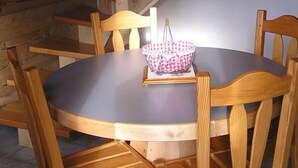 A wooden dining table with chairs, a checkered tablecloth, and a picture frame. A staircase with wooden steps and metal railings is visible in the background. - CHALET COCOON - ALBIEZ MONTROND (ALBIEZ MONTROND)