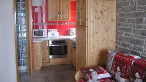 A compact kitchen with wooden cabinets, a microwave, and a stove. - CHALET COCOON - ALBIEZ MONTROND (ALBIEZ MONTROND)