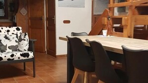 Un comedor con una mesa y sillas de madera, un sofá estampado con diseño de vaca, y un póster en la pared.