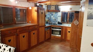 Una cocina compacta con armarios de madera, horno integrado y salpicadero de azulejos.