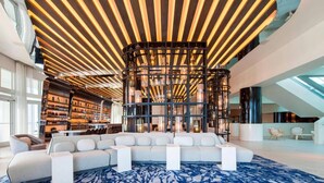 A modern interior with a sectional sofa, a patterned rug, and a ceiling with linear lighting.