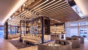 A spacious lobby with a high ceiling, modern lighting, a seating area, and a bar.