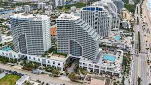 A high-rise hotel with a curved facade, multiple balconies, and a pool area.