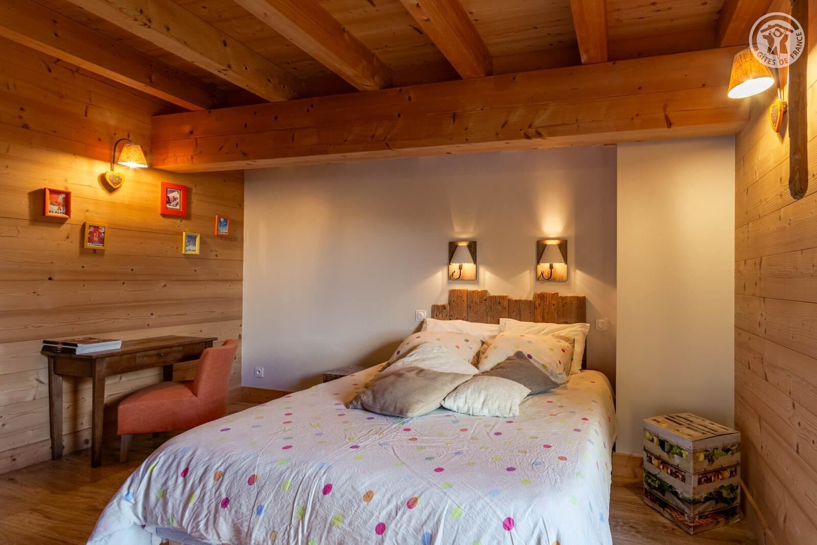 Een gezellige houten kamer met een bed, een bureau en twee wandlampen.
