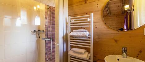 Une salle de bain équipée d’une douche, d’un porte-serviettes, d’un lavabo et d’un miroir.
