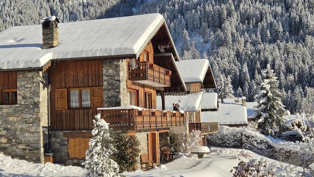 A wooden chalet with stone walls, wooden balconies, and a snow-covered landscape. - LE CHENET DES PIERRES (CHAMPAGNY EN VANOISE)