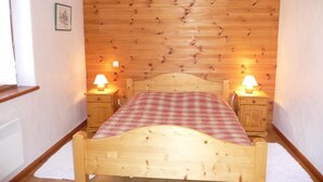 A wooden-paneled room with a bed, two bedside tables with lamps, and a window. - LE CHENET DES PIERRES (CHAMPAGNY EN VANOISE)