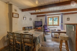 Una habitación acogedora con una mesa de comedor, sillas, un televisor y una ventana con cortinas.