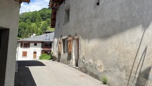 A narrow street with buildings on either side, wooden beams on the roof, and a clear sky. - LA COMBE DE MOULIN - PEISEY NANCROIX (PEISEY NANCROIX)
