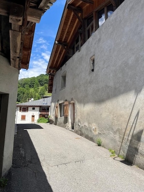 En smal gata med byggnader på båda sidor, träbjälkar i taket och en klar himmel.