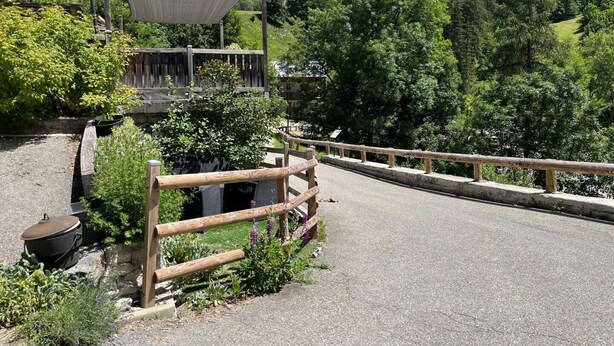 A paved road with a wooden fence, a covered seating area, and a mountain backdrop. - LA COMBE DE MOULIN - PEISEY NANCROIX (PEISEY NANCROIX)