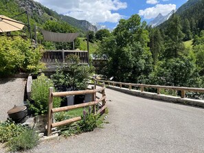 A paved road with a wooden fence, a covered seating area, and a mountain backdrop. - LA COMBE DE MOULIN - PEISEY NANCROIX (PEISEY NANCROIX)