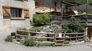 A rustic building with wooden shutters, a stone wall, and a wooden fence. - LA COMBE DE MOULIN - PEISEY NANCROIX (PEISEY NANCROIX)