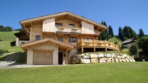 Eine Holzhütte mit Steinfundament, einem Balkon und einer Garage.