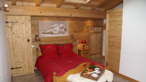 Ein gemütliches Holzzimmer mit einem Bett, einem kleinen Tisch mit Frühstücksbrett und einem Bild an der Wand.