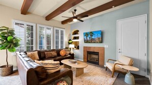 A living room with a brown leather sofa, a coffee table, a fireplace, and a ceiling fan. - Rejuvenating Desert Escape in La Quinta #A (La Quinta)