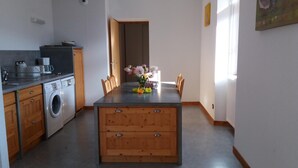 A compact kitchen with a washing machine, wooden cabinets, and a central island with a vase of flowers.