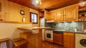 A compact kitchen with wooden cabinets, a built-in oven, a dishwasher, and a sink.