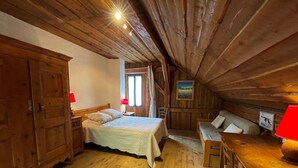 A cozy attic bedroom with a wooden ceiling, a bed, a bench, and a table. - PIERRE BLANCHE - VALMOREL LES AVANCHERS (VALMOREL LES AVANCHERS)