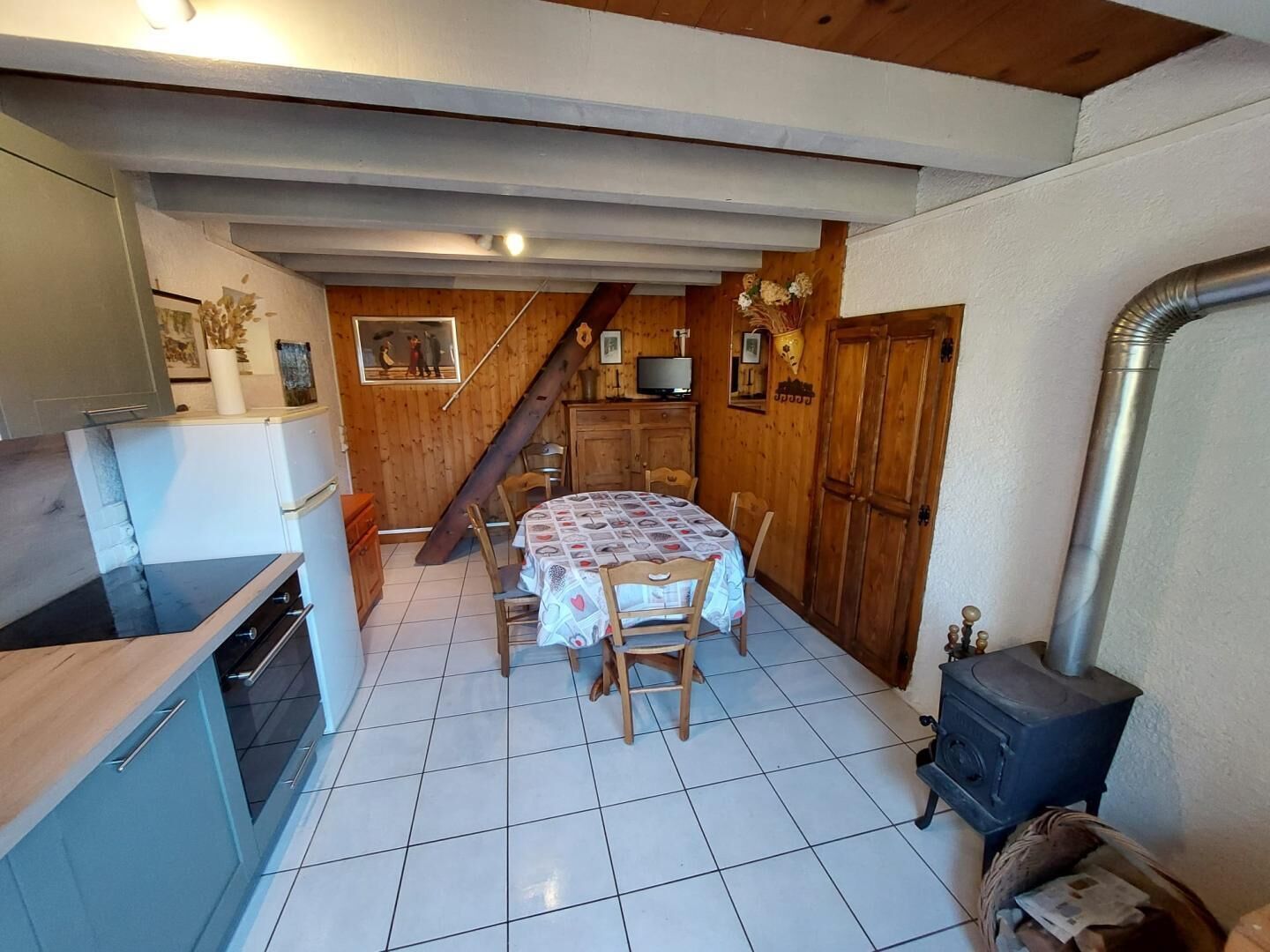 Une cuisine compacte avec un coin repas, un escalier en bois et un poêle à bois.