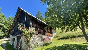 A rustic wooden house with a stone foundation, a balcony with railings, and a garden with flowering plants. - PIERRE BLANCHE - VALMOREL LES AVANCHERS (VALMOREL LES AVANCHERS)