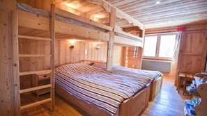 Una baita di legno con un letto a castello, pareti in legno e una finestra.