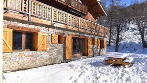 Ein Chalet mit Holzbalkonen und Steinwänden, umgeben von Schnee.
