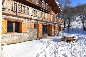 Un edificio in stile chalet con balconi in legno e pareti in pietra, immerso nella neve.