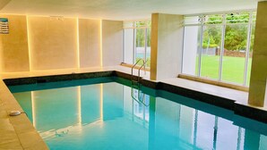 An indoor swimming pool with clear glass walls, a tiled floor, and a window overlooking a green outdoor area. - Stunning Ocean Views from Every Room 
24th level 
Fully Aircond Cental location! (Surfers Paradise)