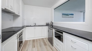 A modern kitchen with white cabinetry, black countertops, and a built-in oven. - Stunning Ocean Views from Every Room 
24th level 
Fully Aircond Cental location! (Surfers Paradise)