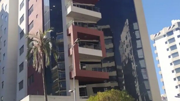A multi-story building with a modern architectural design, featuring a mix of red and white colors, and a prominent vertical element on the facade. - Torre Bossano (Quito)