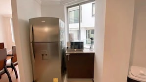 A compact kitchen with a refrigerator, microwave, and sink. - Torre Bossano (Quito)