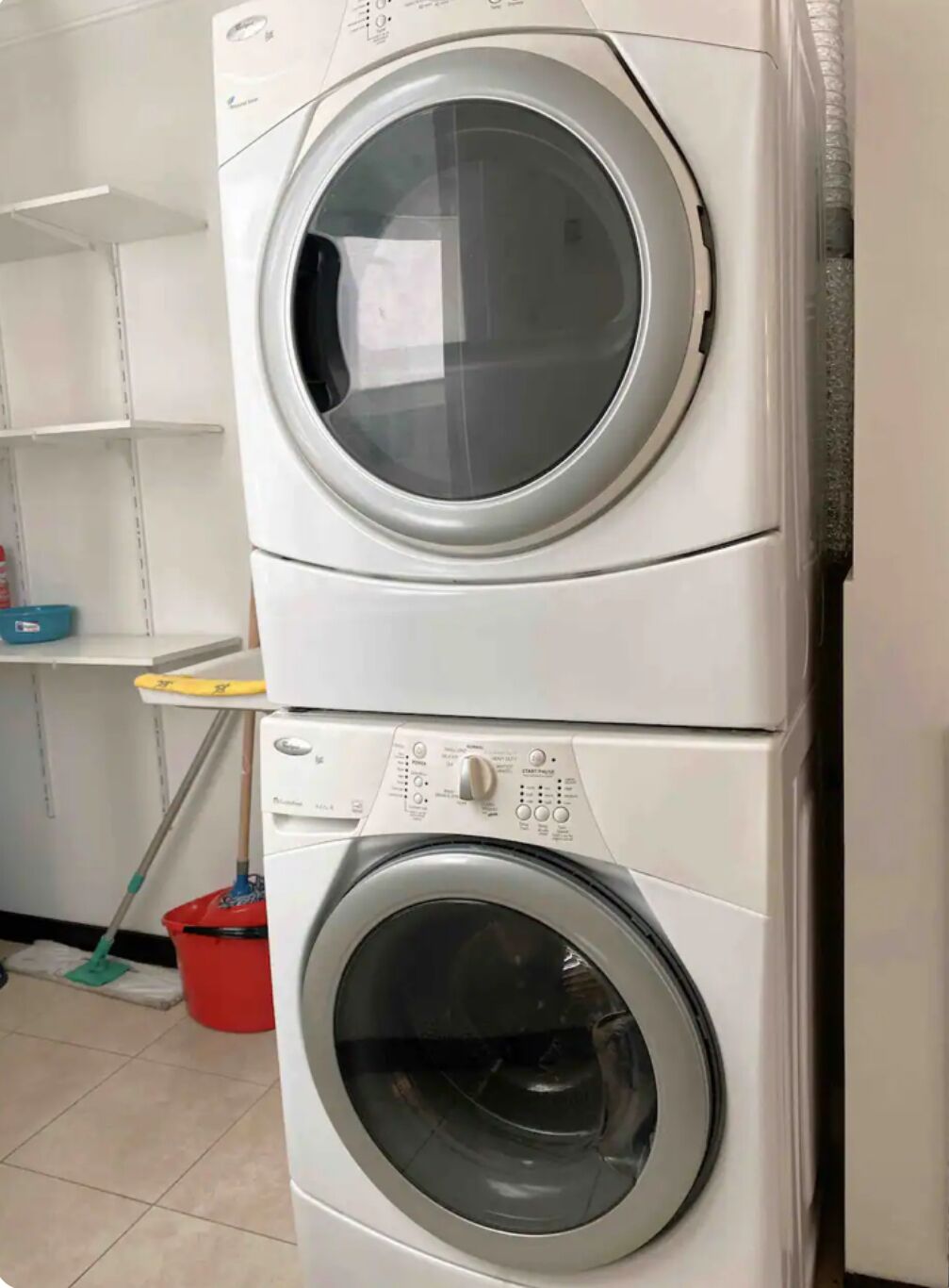 Eine übereinander gestellte Waschmaschine und ein Trockner in einem Waschraum.