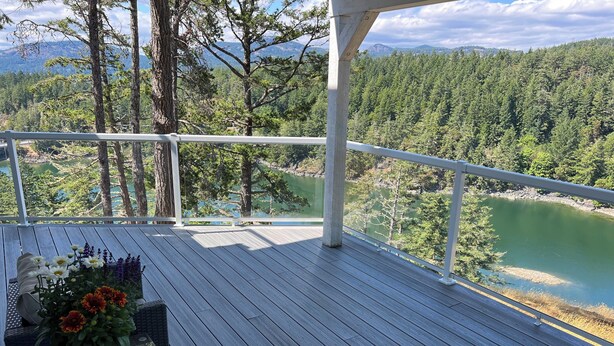 Une terrasse en bois avec une balustrade blanche donnant sur un lac et une forêt.