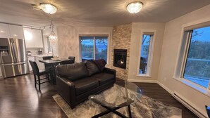 Un salon moderne avec une cheminée, un coin repas et une cuisine.