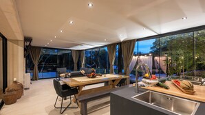 Cozinha moderna com uma ilha grande, área de refeições com banco e vista para o exterior.