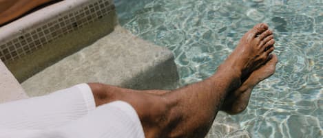 A poolside view with clear water, steps leading into the pool, and a distant landscape.